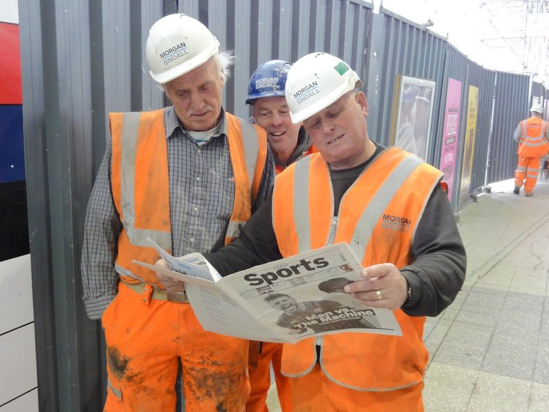 Construction workers looking at a sports-newspaper