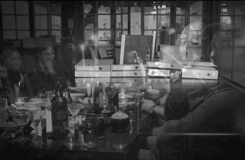 Administrative binders on a table overlaid with a dinner party with people sitting around the same table