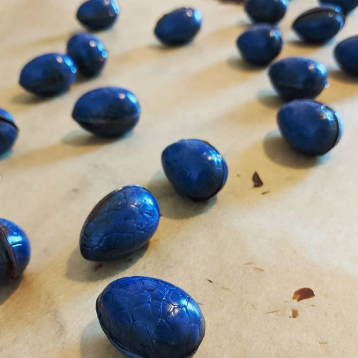 Bright blue chocolate eggs randomly strewn on a table.